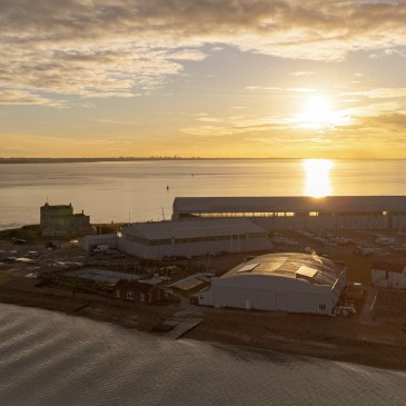Calshot Spit, Hampshire, UK at sunrise with a yellow sky, showing the spit, the coastguard tower, the hangars and the castle