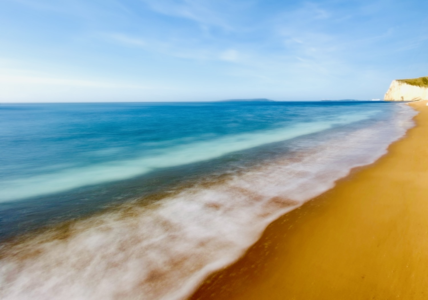 Durdle door beach, long exposure image with turquoise sea and yellow sand and white waves crashing on the shore