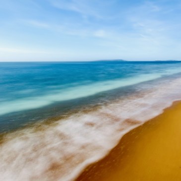 Durdle door beach, long exposure image with turquoise sea and yellow sand and white waves crashing on the shore